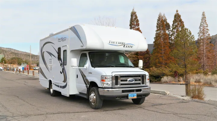 A white Freedom Elite Class C motorhome, ideal for an RV rental adventure, parked on pavement. Nevada plate 822 N73.. Thor Motor Coach Freedom Elite 2018