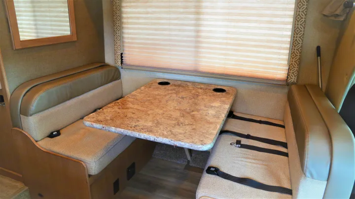 This RV rental dinette offers comfortable seating with seatbelts and a table with cupholders, perfect for meals on the road.. Thor Motor Coach Freedom Elite 2018