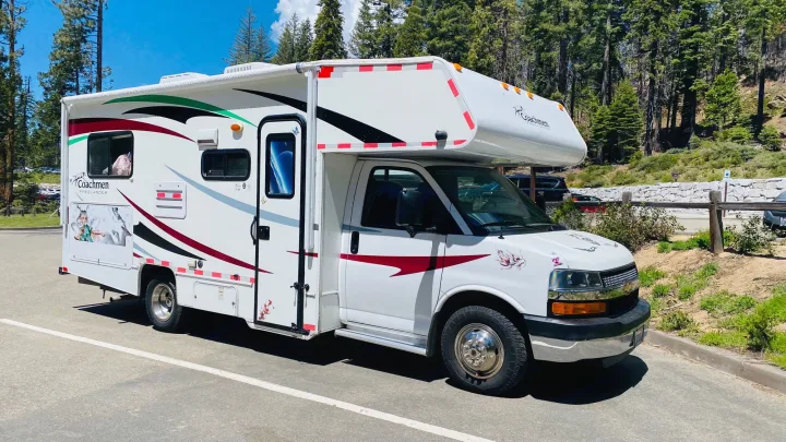 White Coachmen Freelander RV rental parked in a sunny mountain lot with trees. Perfect for your next adventure!. Coachmam Freelander 21QB 2012