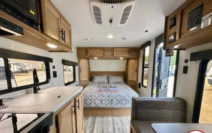 Inside a cozy RV rental, featuring a comfortable bedroom, compact kitchen, and dinette. Ideal for travel adventures.. Forest River Cherokee Wolf Pup 2023
