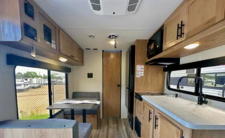 RV rental interior: a comfortable dinette, compact kitchen with appliances, and ample overhead storage. Ready for adventure!. Forest River Cherokee Wolf Pup 2023