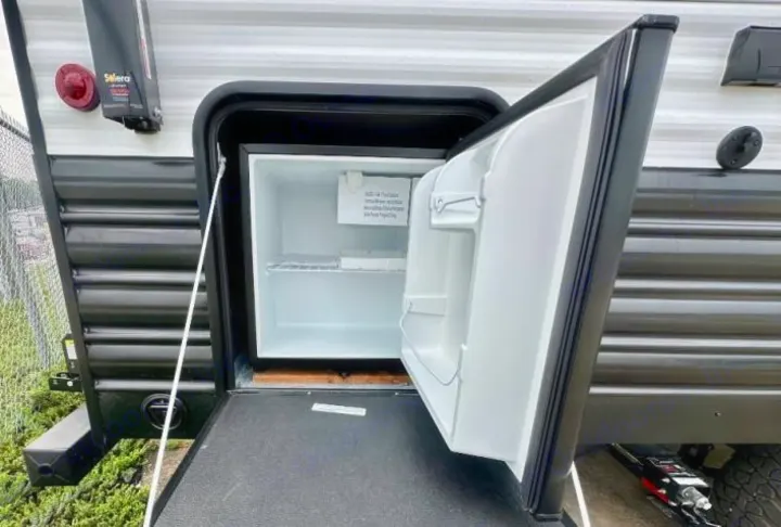 This RV rental features an outdoor mini-fridge within an open compartment, ideal for chilling your camping essentials.. Forest River Cherokee Wolf Pup 2023