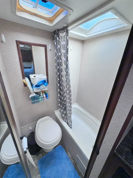 Compact RV rental bathroom with toilet, small tub, mirror, and skylights. Essential for comfortable travel accommodations.. Jayco Jay Flight SLX 2016