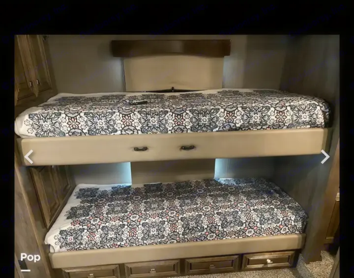 RV rental bunk beds with patterned coverings for compact sleeping areas.. Fleetwood Discovery LXE 2020
