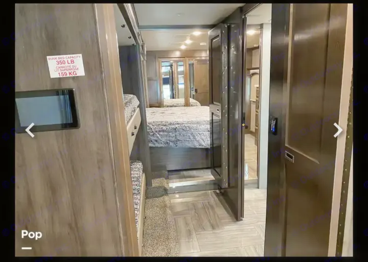 Spacious RV rental interior features modern bunk beds, a master bedroom with mirrored closets, and stylish flooring.. Fleetwood Discovery LXE 2020