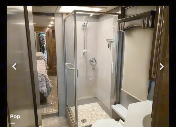 Modern RV rental interior: full bathroom with glass shower, and adjacent bedroom with twin beds. Perfect for travel.. Fleetwood Discovery LXE 2020