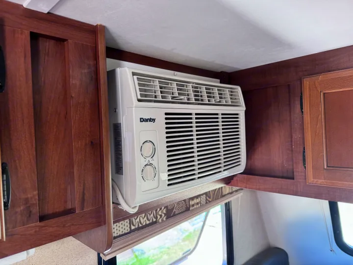 A compact Danby AC unit is built into the wooden overhead cabinets of an RV rental, providing essential cooling for your trip.. Jayco Jay Flight SLX 2016