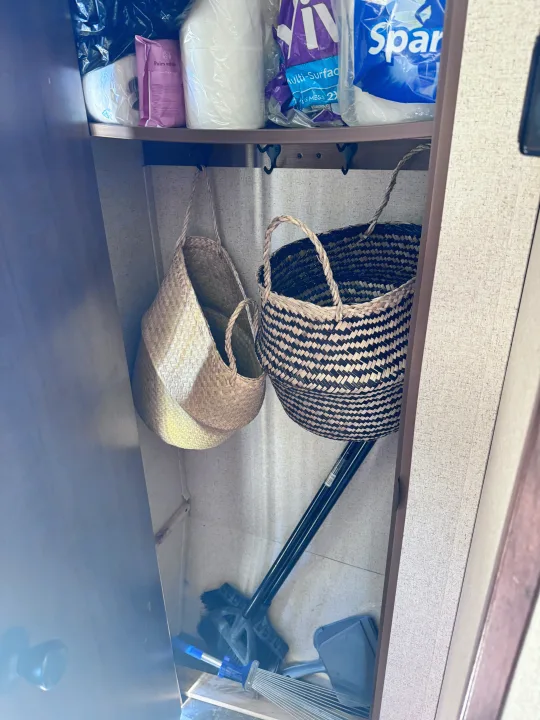 RV rental closet showing practical storage: paper products, cleaning supplies, and woven baskets with hooks for organization.. Jayco Jay Flight SLX 2016