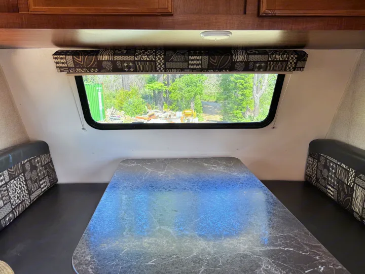 RV rental interior: A dinette area with a marbled table, patterned bench cushions, and a large window overlooking trees.. Jayco Jay Flight SLX 2016