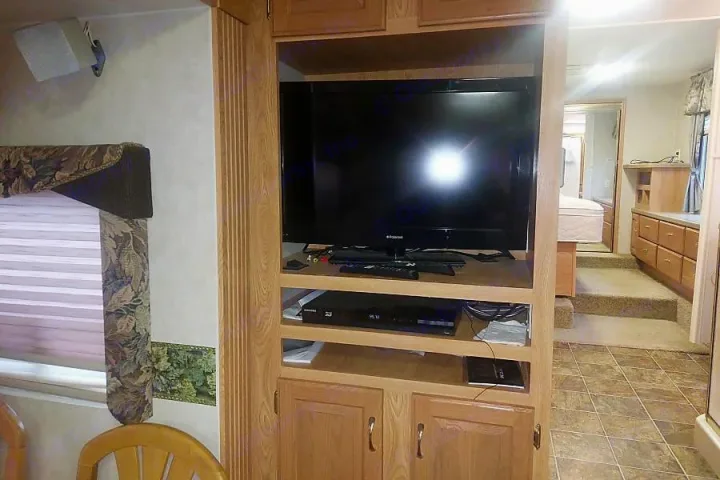 RV rental interior: TV entertainment center in living area, with bedroom access via steps. Enjoy comfort on the road.. Crossroads Silverado 2005