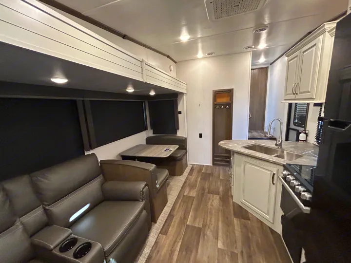 RV rental: Modern interior with dark gray recliners, booth dinette, and full kitchen. Perfect for a cozy road trip.. Keystone RV Cougar 2023