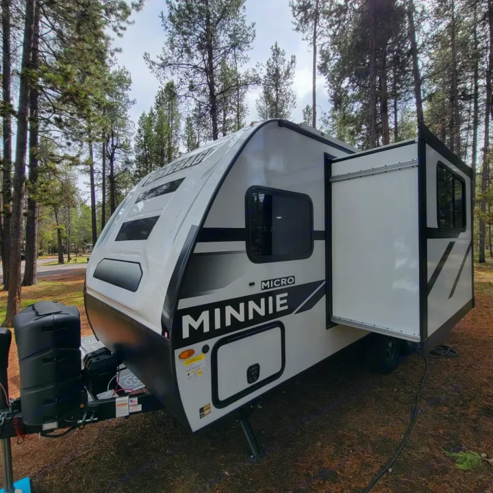 Modern Minnie Micro RV rental set in a peaceful pine forest campground. Features a slide-out for more room.. Minnie Micro Minnie 2023