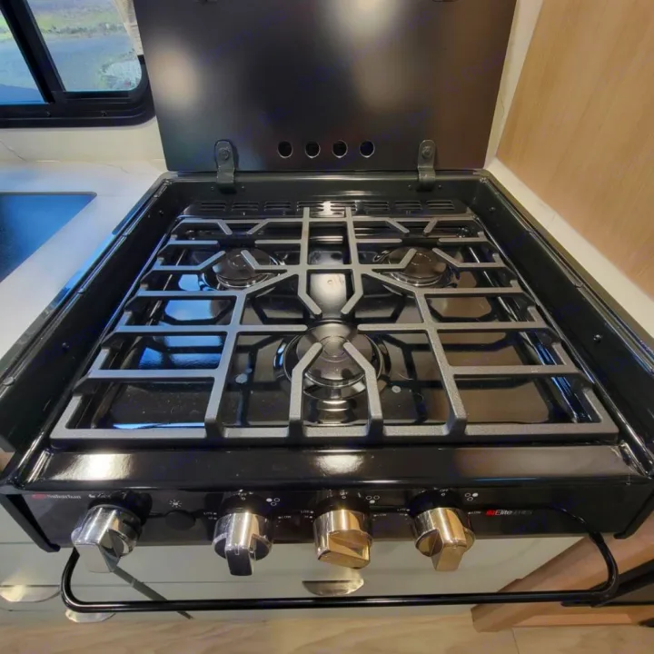 RV rental kitchen featuring a clean, black three-burner gas stovetop with control knobs and an open lid.. Minnie Micro Minnie 2023