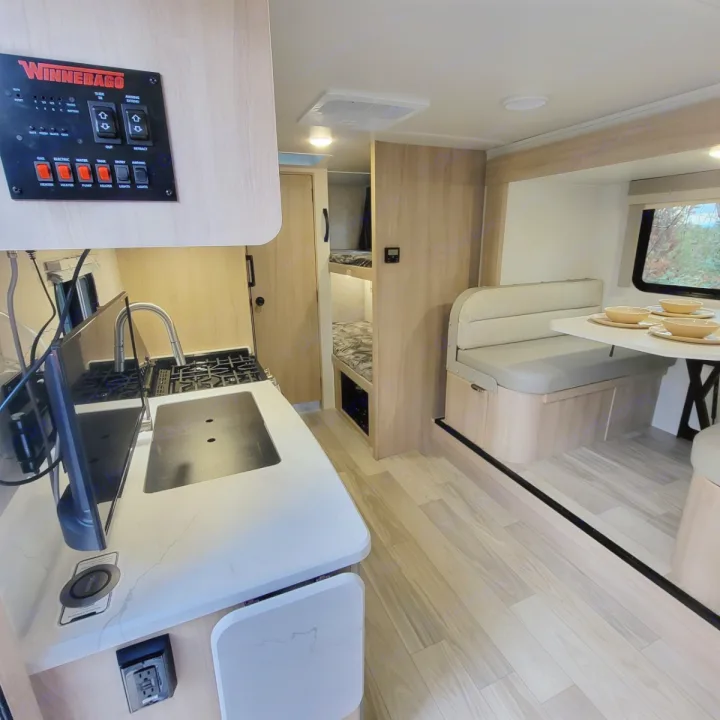 Winnebago rv rental interior: modern kitchen, dining booth, and bunk beds, ideal for travel adventures.. Minnie Micro Minnie 2023