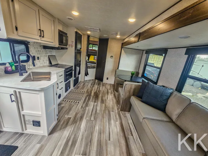 Spacious, modern RV rental interior with a full kitchen, dining area, and comfortable living space, perfect for travel.. Highland Ridge RV Open Range 2024