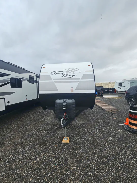 Discover outdoor adventures with this white Open Range travel trailer, an ideal RV rental parked on a gravel lot under a cloudy sky.. Highland Ridge RV Open Range 2024