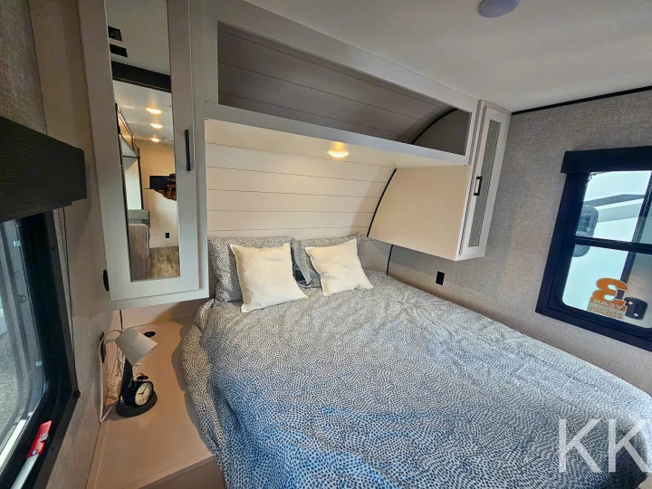 This RV rental's inviting bedroom offers a comfortable bed, ample storage, and mirrored closet for your adventures.. Highland Ridge RV Open Range 2024