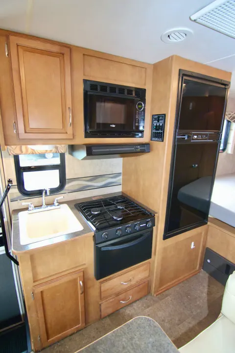 RV rental kitchen: compact interior with microwave, range, sink, and fridge. Ideal for on-the-go meals and comfort.. Winnebago Minnie Winnie 2016