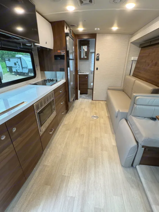 Spacious and modern RV rental interior: galley kitchen with appliances, sofa living area, and bathroom access.. Winnebago View 2022