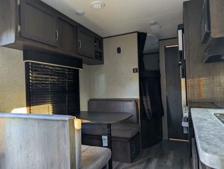 Modern RV rental interior with dinette, kitchen, and curtained bunk area, ideal for comfortable travel.. Jayco Jay Flight SLX 2021