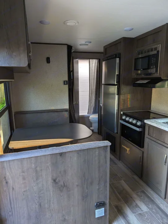 Spacious RV rental interior with modern kitchen, dining booth, and bathroom access, perfect for travel.. Jayco Jay Flight SLX 2021