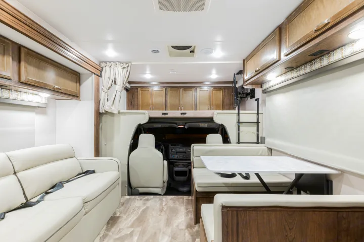 Inside a modern RV rental, showing a comfortable lounge, dinette seating, overhead storage, and a bunk bed.. Gulf Stream Yellowstone 2023