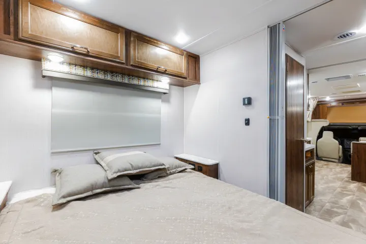Spacious RV rental bedroom with a comfy bed, overhead cabinets, and bright, modern decor.. Gulf Stream Yellowstone 2023