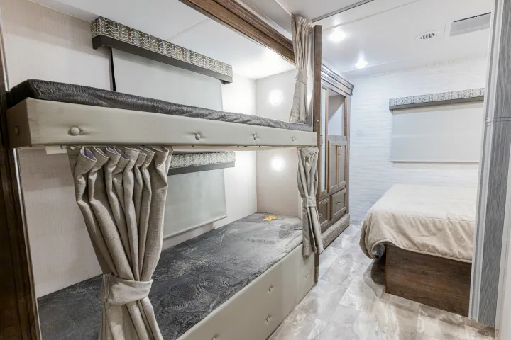 Modern RV rental bedroom with bunk beds, privacy curtains, and a comfortable main bed. Ideal for family adventures.. Gulf Stream Yellowstone 2023