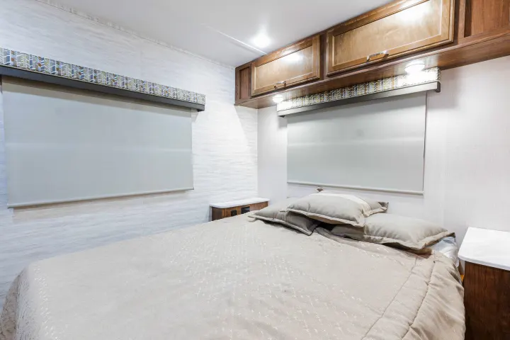 Spacious RV rental bedroom with a cozy bed, ample overhead storage, and privacy shades for a relaxing journey.. Gulf Stream Yellowstone 2023