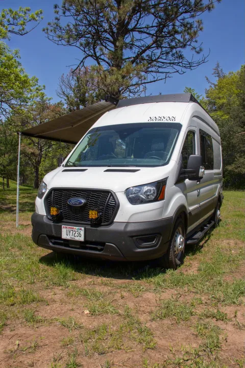 White Ford Transit camper van RV rental with awning extended, perfect for outdoor camping.. Ford Transit 2023
