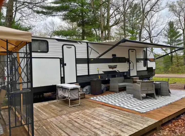RV rental setup with deck, outdoor seating, and awning extended for comfortable camping.. Forest River Wildwood 2021
