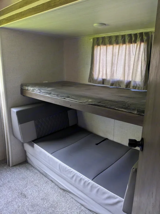 RV rental's cozy bunk beds, featuring a top bed and a convertible lower sofa, ideal for extra sleeping space in a travel trailer.. Forest River Wildwood 2021
