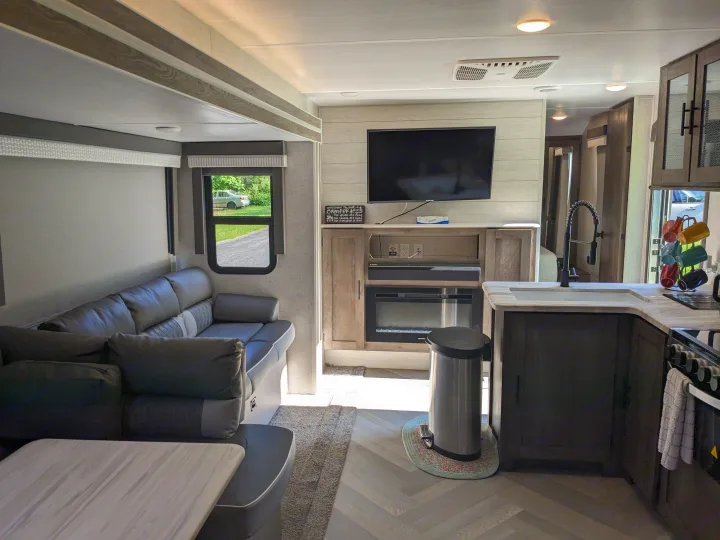 Experience comfort in this modern RV rental interior, complete with a living area, kitchen, TV, and fireplace.. Forest River Wildwood 2021
