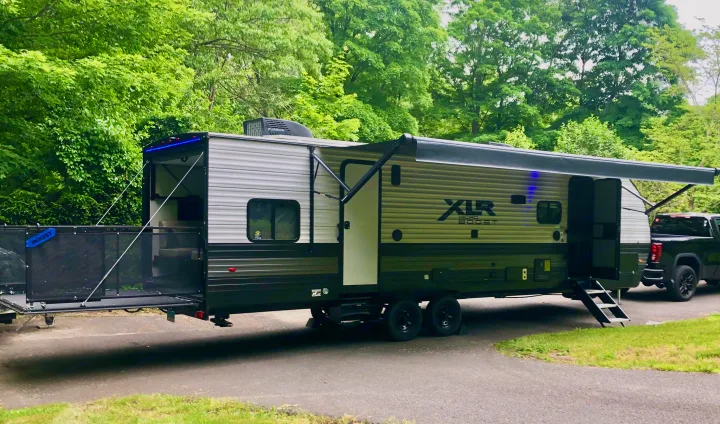 Ready for adventure! This XLR Micro Boost RV rental is fully set up at a scenic campsite with its awning out and ramp down.. Forest River Xlr Thunrderbolt 2022