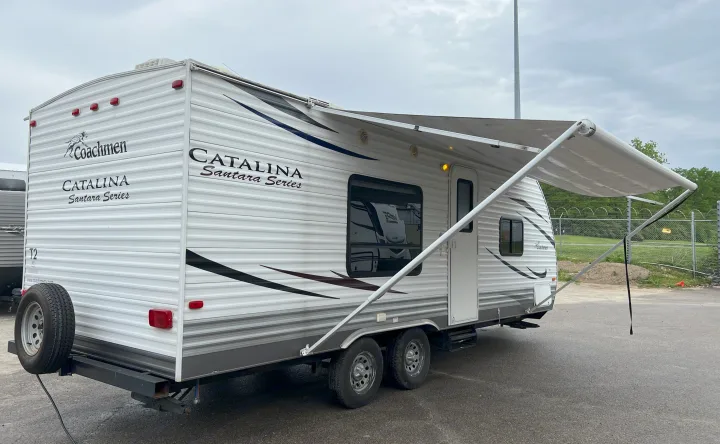 A white Coachmen Catalina Santara Series travel trailer, with an extended awning, parked on asphalt. Great for RV rental.. Coachmen Catalina 2012