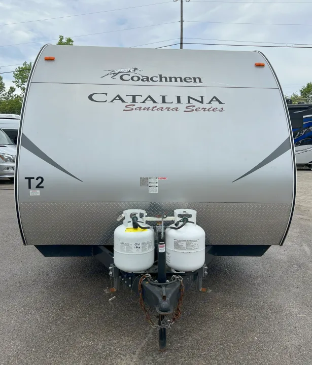 Front of a Coachmen Catalina travel trailer for RV rental, showing two propane tanks, a hitch, and diamond plate.. Coachmen Catalina 2012