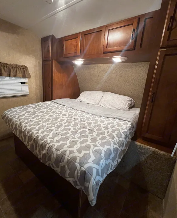 Comfortable RV rental bedroom with a cozy queen bed, overhead storage cabinets, and soft lighting for relaxing travel.. Coachmen Catalina 2012