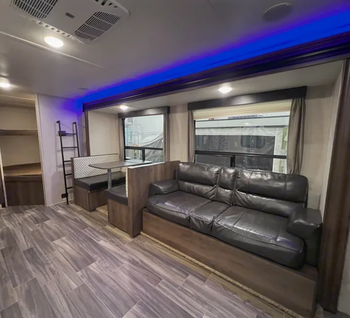 Inside this RV rental: comfortable sofa, dinette, and bunk beds, with blue ambient lighting.. Forest River Shasta 26DB 2020