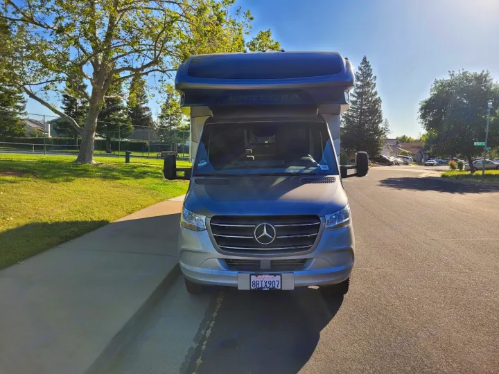 Front view of a silver Mercedes-Benz Entegra RV rental parked by a sunny park. Ready for adventure!. Entegra Coach Qwest 2020