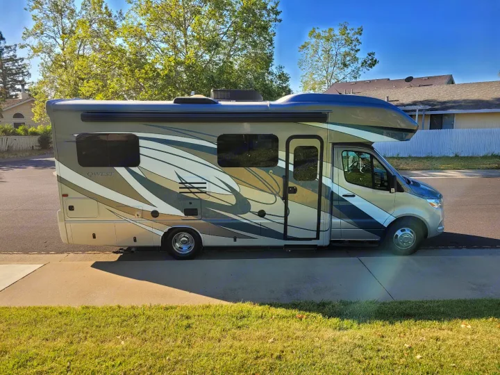 Sleek, modern RV rental motorhome parked on a sunny street, featuring a unique abstract graphic design for your next adventure.. Entegra Coach Qwest 2020
