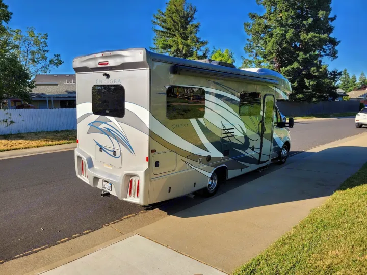 Spacious Entegra Qwest motorhome, an RV rental option, with stylish gray and green graphics, parked on a sunny street.. Entegra Coach Qwest 2020