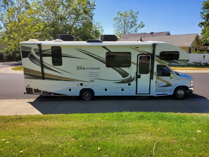 White Jayco Greyhawk Class C RV rental with graphic decals parked on a sunny day, ready for travel adventures.. Jayco Greyhawk 2021