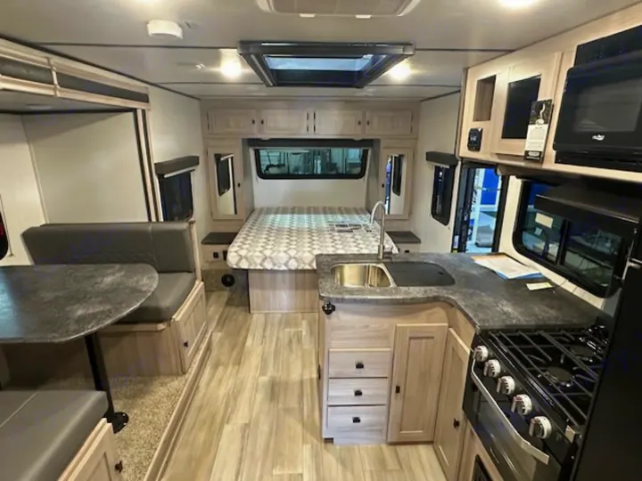 Spacious rv rental interior showing kitchen, dining, and bedroom areas. Light wood cabinets and modern appliances visible.. Coachmen 2146BHX 2023