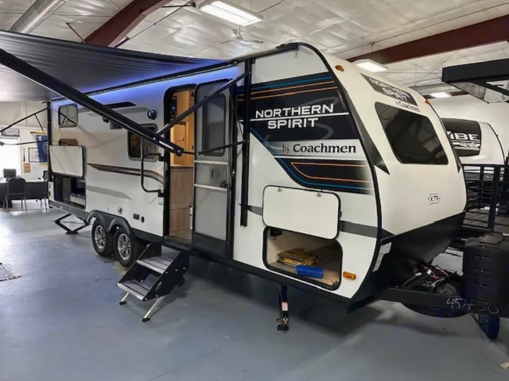 Bright Coachmen Northern Spirit travel trailer, perfect for RV rental. Features lighted awning, open storage, and steps.. Coachmen 2146BHX 2023