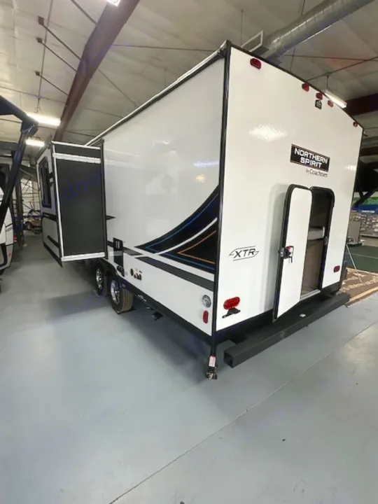 White Northern Spirit XTR travel trailer, showing its rear ramp door & extended slide-out, ideal for rv rental.. Coachmen 2146BHX 2023