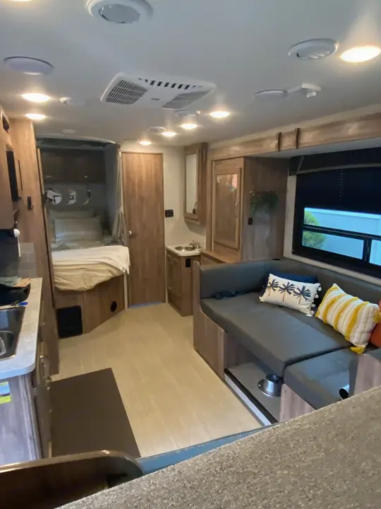 This RV rental interior shows a compact layout with a bedroom, dinette, and kitchen area, perfect for travel.. Jayco Redhawk SE 2021