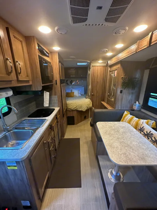 View inside a modern RV rental, featuring a compact kitchen, dining area, and cozy rear bedroom.. Jayco Redhawk SE 2021
