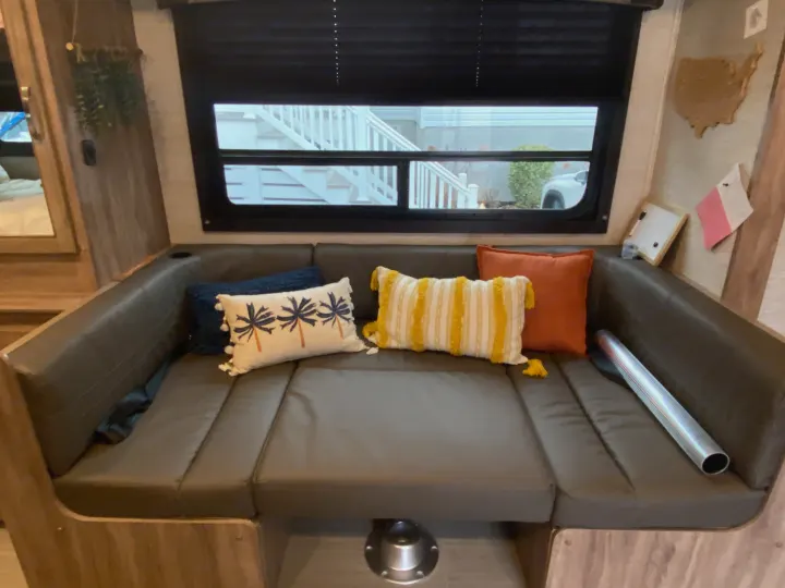 Cozy RV rental dinette area with U-shaped seating, colorful pillows, and window views. Converts to a bed for comfort.. Jayco Redhawk SE 2021