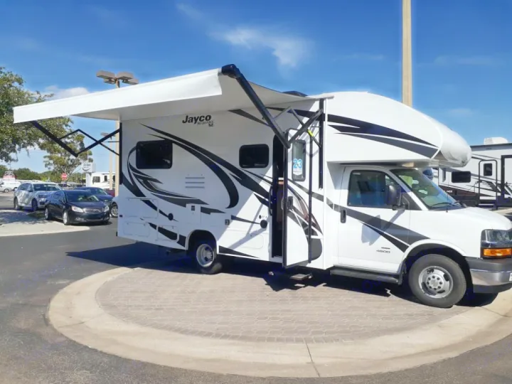 Bright white Jayco Class C motorhome with its awning extended, parked outdoors, an excellent RV rental.. Jayco Redhawk SE 2021