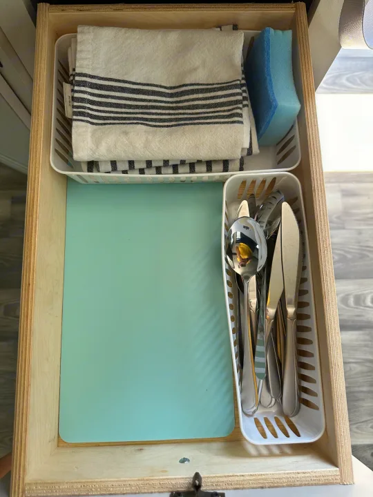 An RV rental drawer neatly stores kitchen essentials: towels, a sponge, a cutting board, and silverware.. Highland Ridge RV Open Range 2022